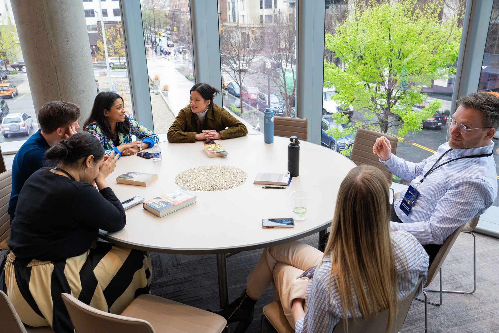 people talking at round table next to large window