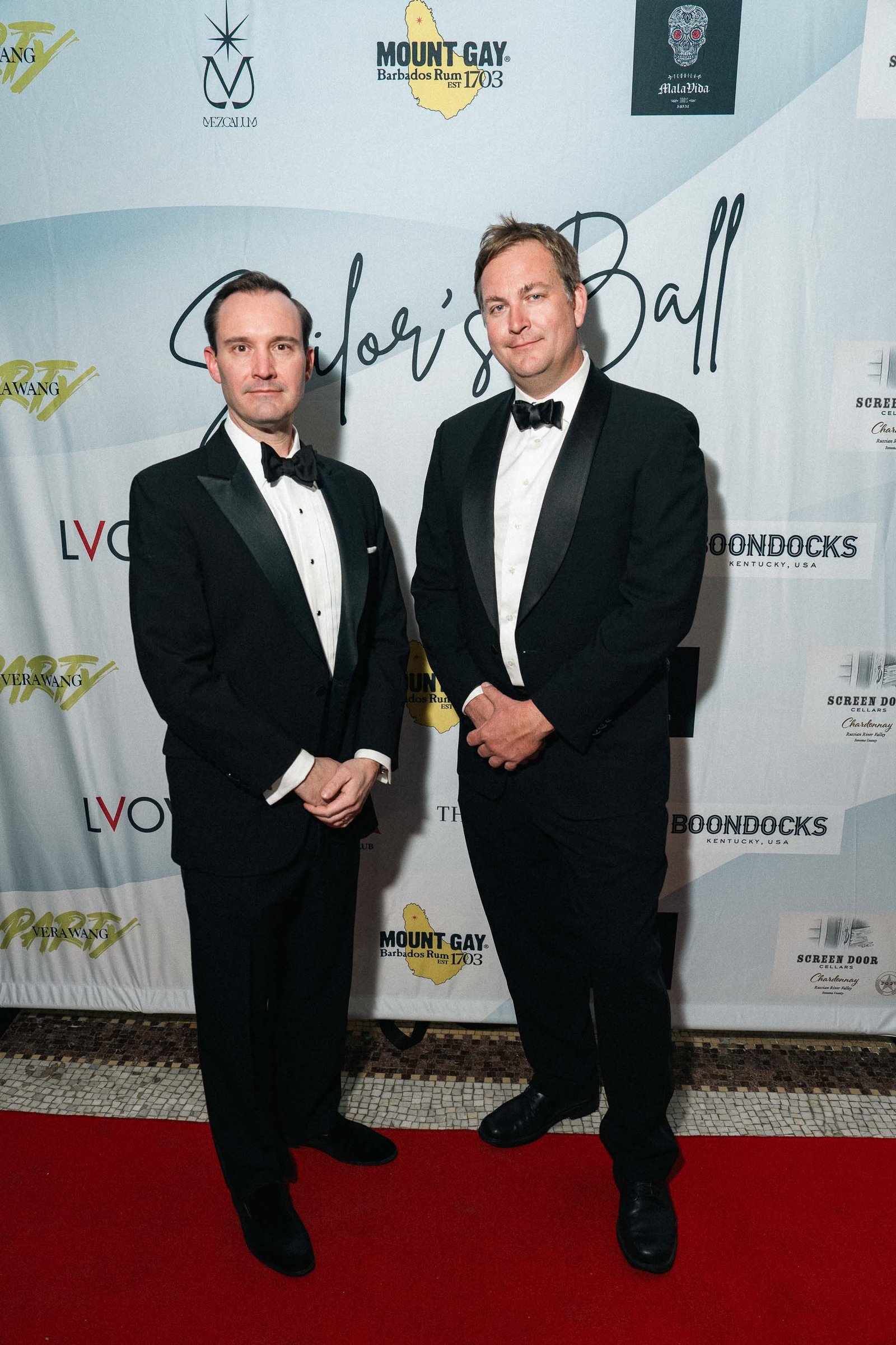 Two men in tuxedos at Sailor's Ball 2024 red carpet New York City