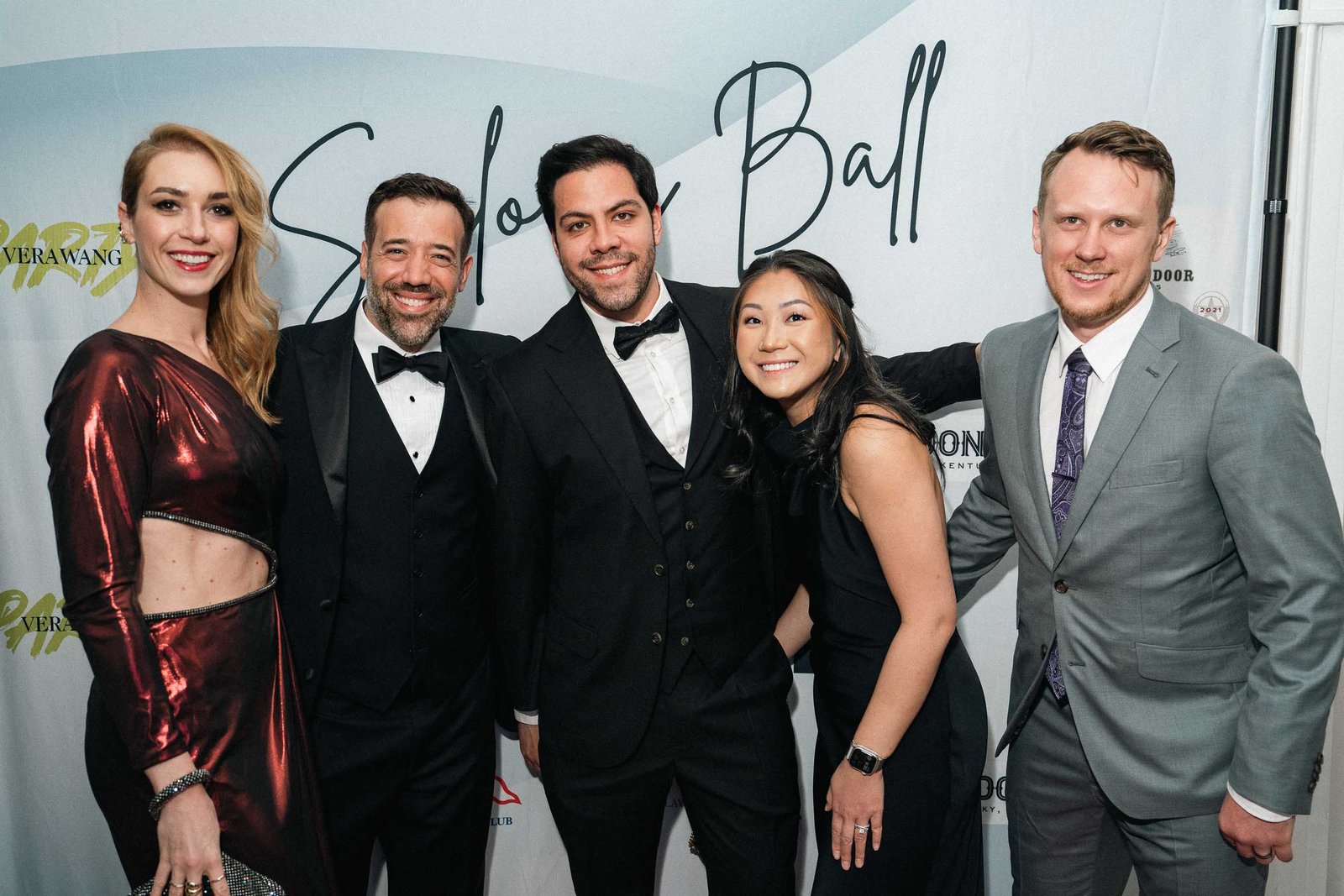 Group of guests in formal attire at Sailor's Ball 2024 photo wall NYC