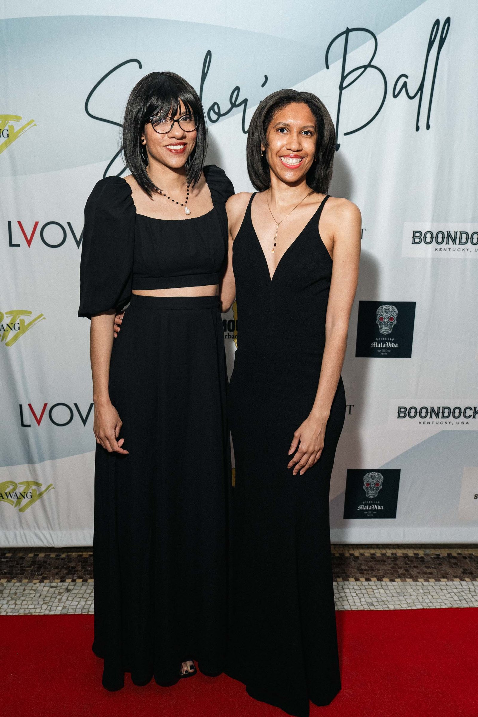 Two women in black formal wear at Sailor's Ball 2024 red carpet New York City