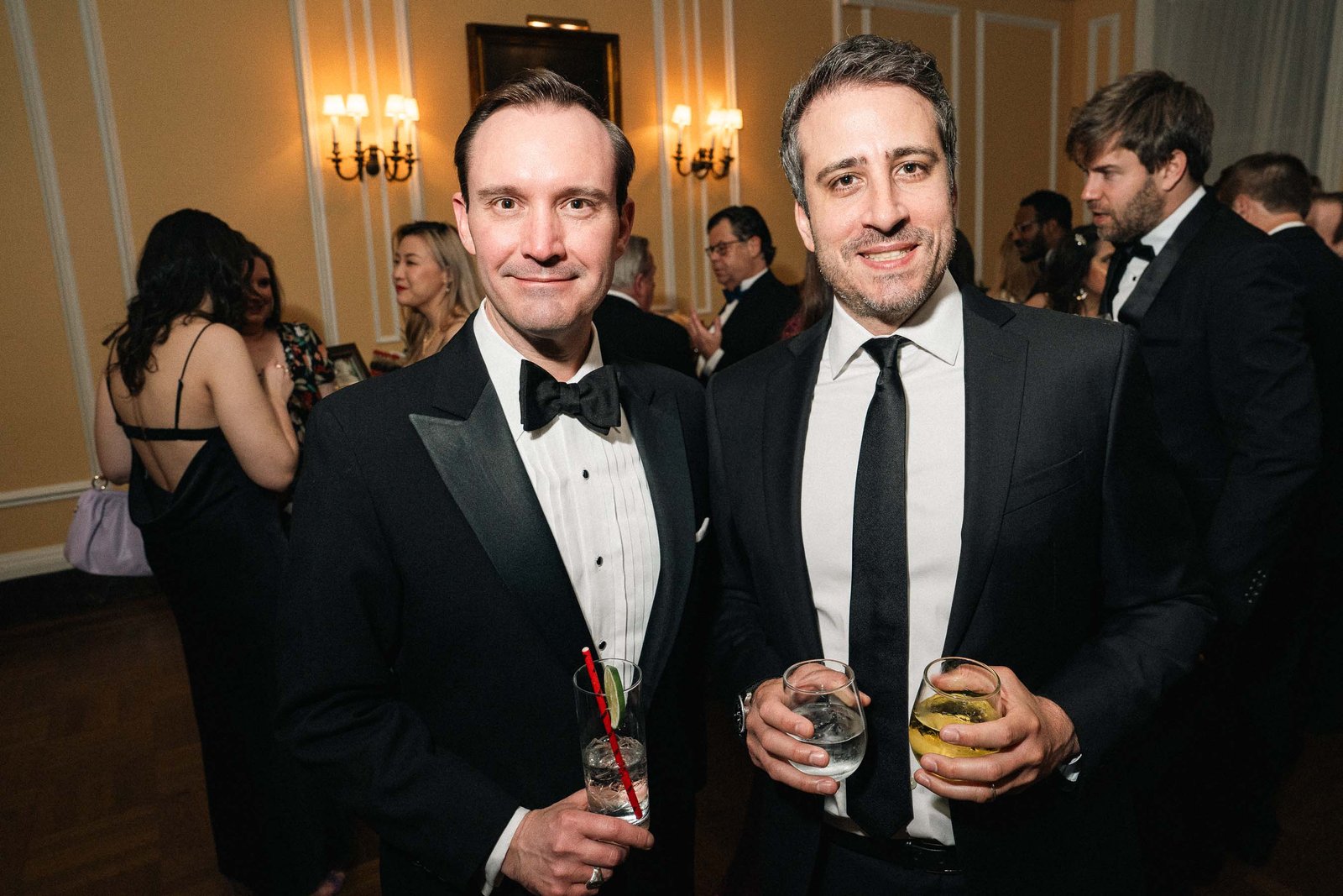 Two men in tuxedos with drinks at Sailor's Ball 2024 NYC gala