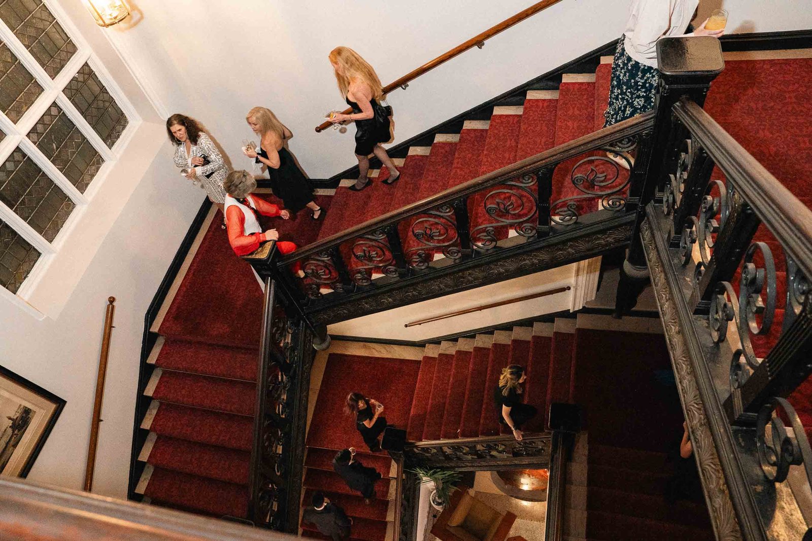 Woman in red gown on grand staircase at Sailor's Ball 2024 New York City