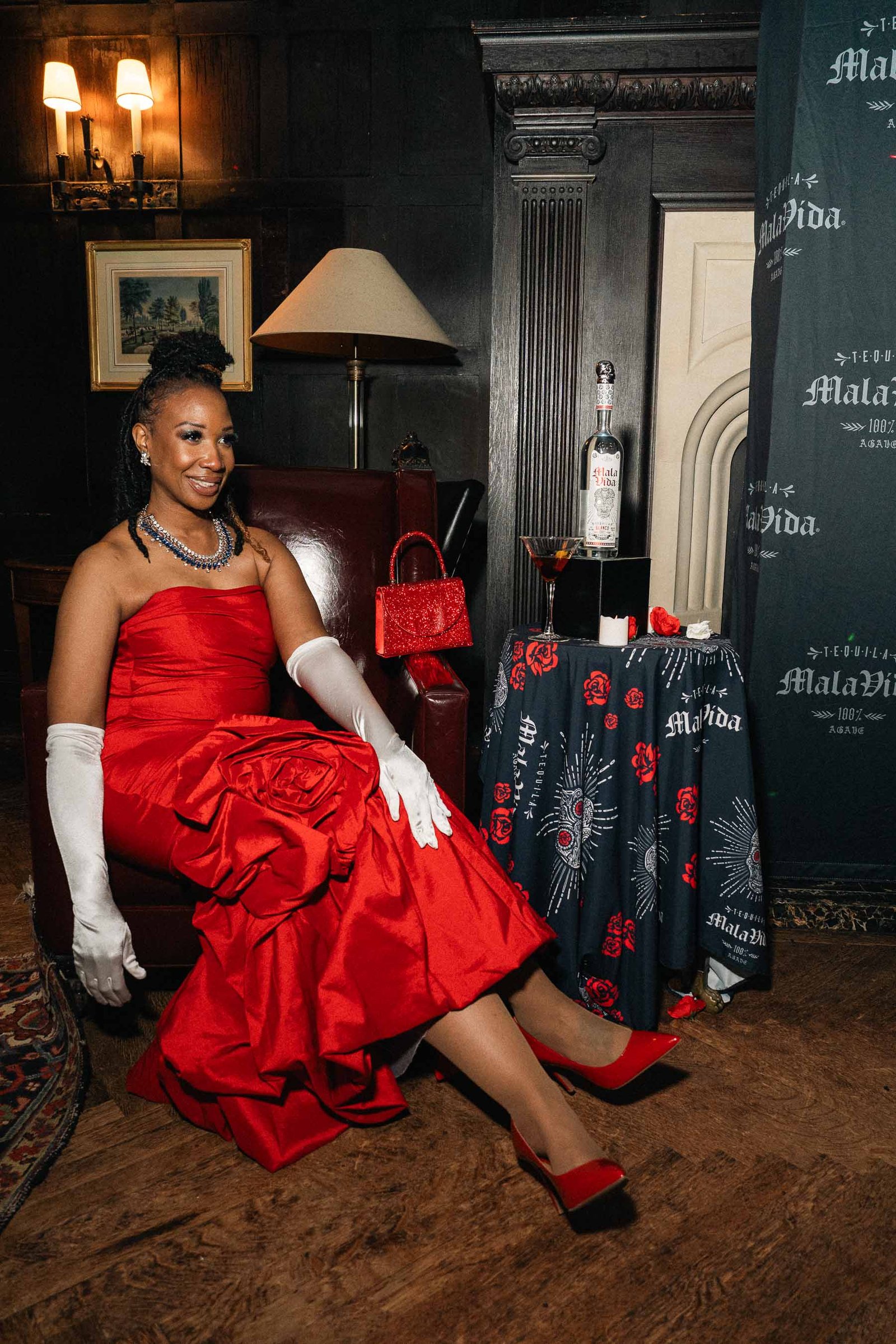 Woman in red gown seated on staircase at Sailor's Ball 2024 New York City