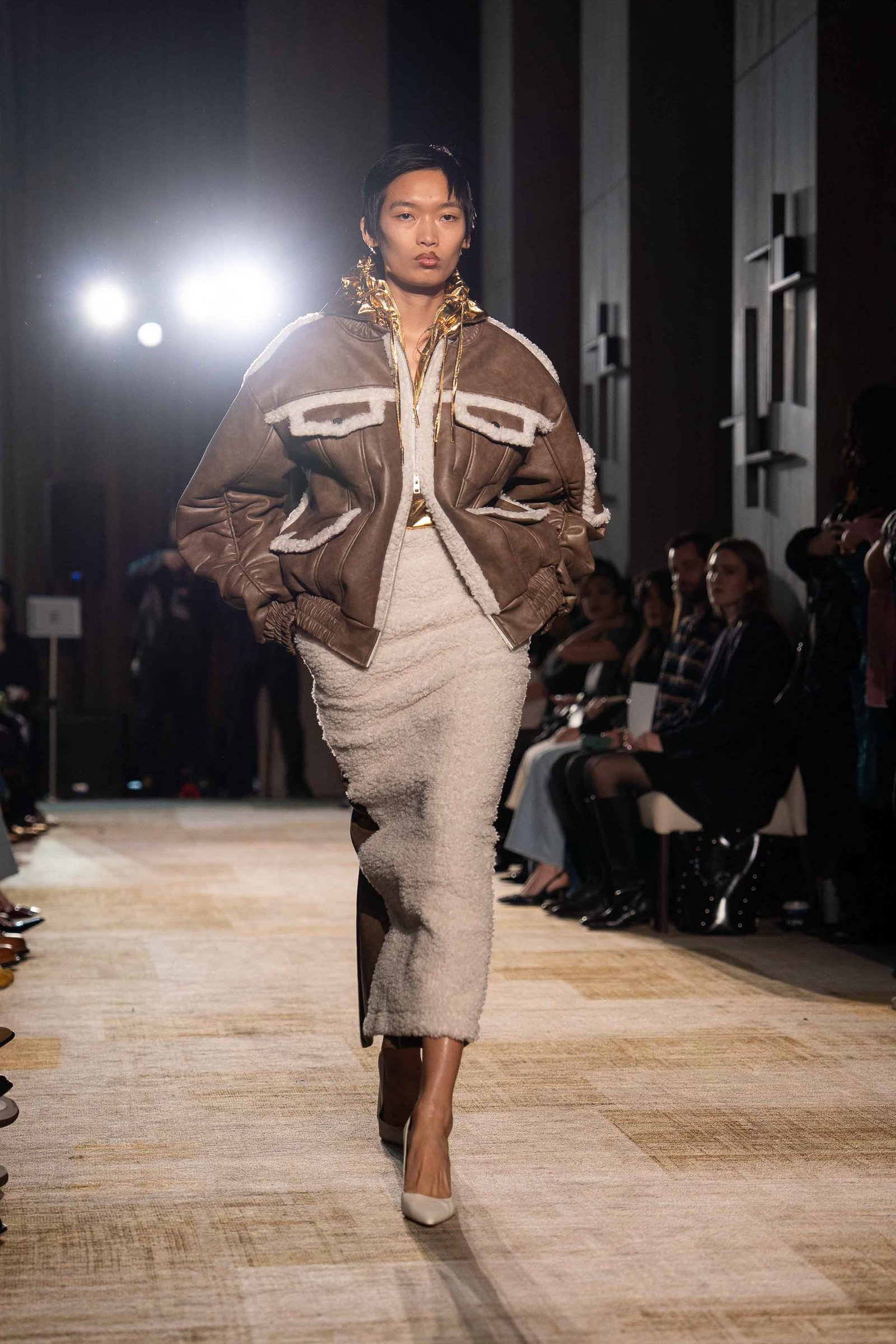 Aknvas model in brown jacket walking the runway New York Fashion Week